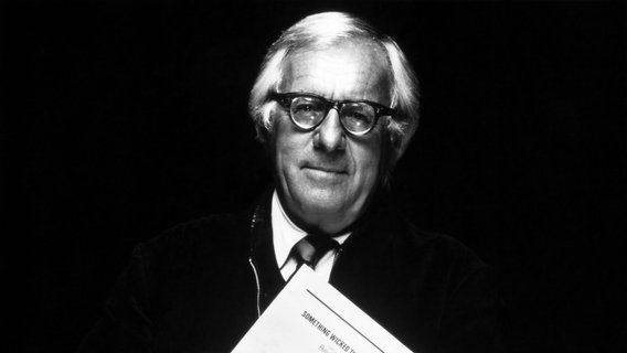 Einälterer Herr mit grauem Haar und einer kleinen Brille mit dicken Gläsern hält ein Skript im Arm. © IMAGO / Everett Collection 