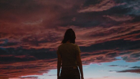 Eine Frau steht vor einem dramatisch beleuchteten Himmel. © Daniel Chiang / photocase.de Foto: Daniel Chiang