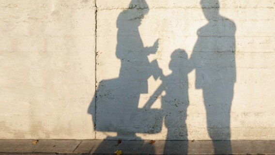 Familie wirft einen Schatten auf eine Betonwand. © krockenmitte / photocase.de Foto: krockenmitte