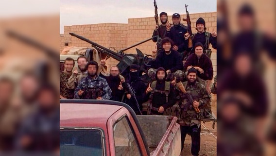 Eine Gruppe von IS-Kämpfern posieren mit Waffen.  
