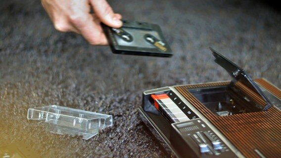 Eine Person legt eine Kassette in ein Abspielgerät ein. © photocase Foto: complize
