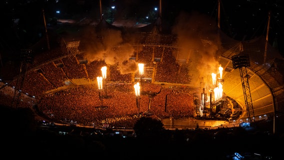 Das Münchener Olympiastadion im Dunkeln mit Flammen auf der Bühne. © picture alliance/dpa | Sven Hoppe 
