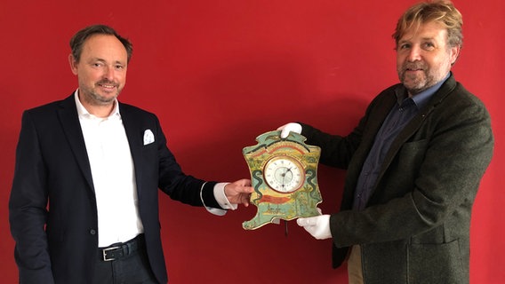 Stephan Kolschen, Geschäftsführer der Brune-WZ-Stiftung, und Stephan Huck, Leiter des Deutschen Marine Museums in Wilhelmshaven, präsentieren die Deutsche Reichs-Colonial-Uhr Stephan Kolschen, Geschäftsführer der Brune-WZ-Stiftung, und Stephan Huck, Leiter des Deutschen Marine Museums in Wilhelmshaven, präsentieren die Deutsche Reichs-Colonial-Uhr © NDR Foto: Jutta Przygoda