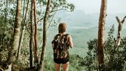 Eine Backpackerin steht im Urwald © picture alliance / Shotshop Foto: Addictive Stock