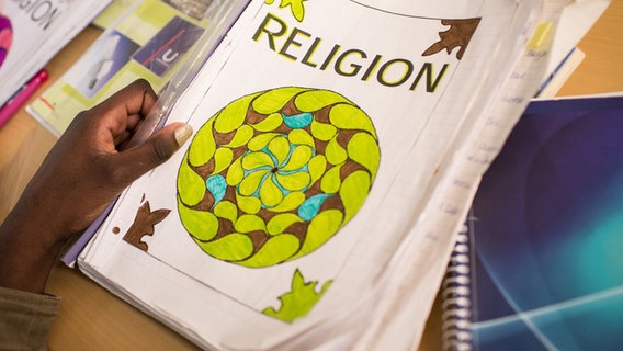 Eine Schulmappe mit einem Deckblatt, auf dem das Wort "RELIGION" zu lesen ist © Maria Feck 