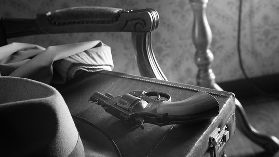 Eine Waffe liegt auf einem Koffer. © panthermedia_35660795_dpcrestock 
