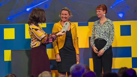 Katja Marx überreicht den Preis an Annika Joeres und Susanne Götze. © NDR Foto: Axel Herzig