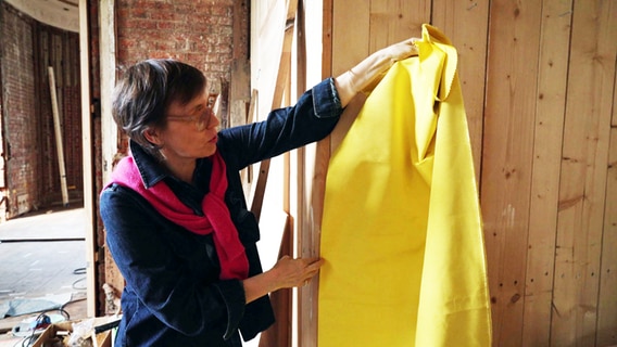 Die Textilrestauratorin Ines Zimmermann zeigt den gelben Stoff für den Alkoven. © NDR 