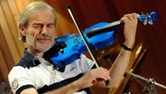 Der Geiger Jean-Luc Ponty spielt mit geschlossenen Augen auf einer blauen Violine. © imago/Xinhua Foto: Xinhua