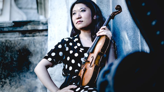 Tianwa Yang schaut sitzend mit ihrer Violine in der Hand versunken nach vorn. © Andrej Grilc Foto: Andrej Grilc