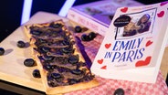 Französische Sardellen-"Pizza" neben einem Kochbuch zu "Emily in Paris" - Folge 80 von eat.READ.sleep © NDR Foto: Claudius Hinzmann