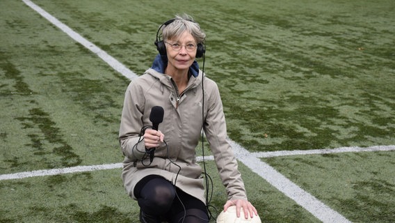 Martina Keller mit Reportermikro und Ball auf einem Fussballfeld. © Leo Schulte Foto: Leo Schulte