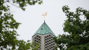 Der Turm der Moschee der Al-Nour-Gemeinde, der ehemaligen Kapernaumkirche,  mit dem goldenen arabischen Schriftzug für Allah ist in Hamburg-Horn hinter Bäumen zu sehen. © picture allience, dpa Foto: Daniel Bockwoldt