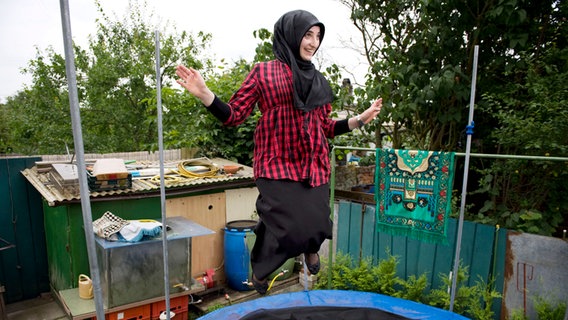 Muslimin auf einem Trampolin im Schrebergarten. © Emine Akbaba 