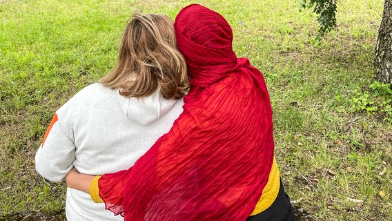 Zwei Frauen sitzen en aneinander geschmiegt auf einer Wiese. © Kadriye Acar Foto: Kadriye Acar
