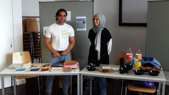 Ein junger Mann und eine junge Frau hinter einem Stand  in der Uni. © NDR Foto: Hans Stallmach