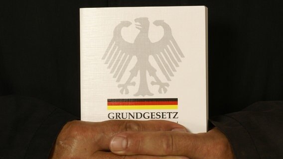 Hände umschließen das Grundgesetzbuch. © picture-alliance Foto: M. Stolt / CHROMORANGE