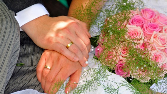 Zwei Hände mit Hochzeitsringen am Ringfinger und ein Strauß mit rosafarbenen Rosen © picture alliance / imageBROKER Foto: Bernhard, A.