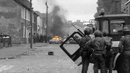 Ein brennendes Auto in Belfast im Mai 1981, im Vordergrund britische Truppen. © picture alliance / ASSOCIATED PRESS | Anonymous (m) 