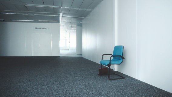 Ein leerer Stuhl steht vor einer Tür mit der Aufschrift "Behandlung 1". © Photocase Foto: joexx