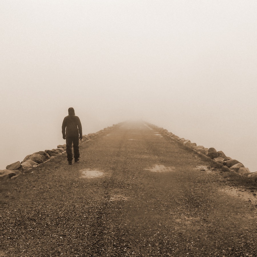 Eine Person geht eine verlassene Straße entlang ins Nichts. © photocase Foto: Alpenfux