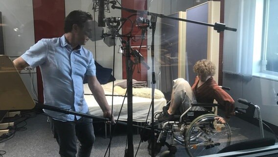 Zwei Personen nehmen im Tonstudio einen Rollstuhl auf. © NDR / Julia Werth Foto: Julia Werth