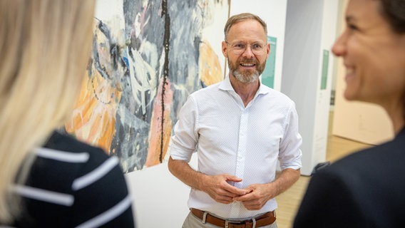 Museumsdirektor Andreas Beitin im weißen Hemd, spricht mit zwei OPersonen, die vor ihm stehen. © Marek Kruszewski Foto: Marek Kruszewski