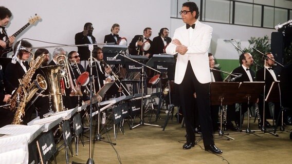 Bandleader Kurt Edelhagen steht vor seinem musizierenden Ensemble "Kurt Edelhagen Orchester" bei einem Auftritt 1972. © picture alliance / dpa Foto: Gerhard Rauchwetter