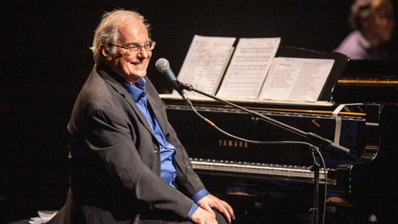 Komponist und Pianist Francis Hime sitzt auf der Bühne an einem Flügel und lächelt ins Publikum. © imago images / Van Campo 
