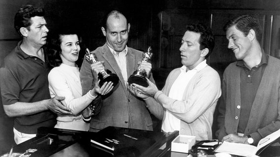 Vier Personen stehen neben dem Filmkomponisten Henry Mancini, der zwei Oscar-Trophäen in den Händen hält. © picture alliance / Everett Collection Foto: CSU Archives/Courtesy Everett Collection