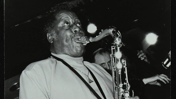 Ein schwarz-weiß Foto von Eddie "Lockjaw" Davis, der sein Tenorsaxofon spielt, auf der Bühne bei einem Konzert 1982. Ein schwarz-weiß Foto von Eddie "Lockjaw" Davis, der sein Tenorsaxofon spielt, auf der Bühne bei einem Konzert 1982. © picture alliance / Heritage Images | National Jazz Archive