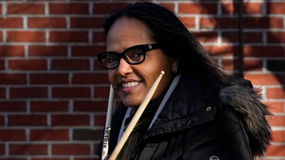 Terri Lyne Carrington lächelt in die Kamera und hält zwei Schlagzeugsticks in ihren Händen. © picture alliance / ASSOCIATED PRESS Foto: Charles Krupa