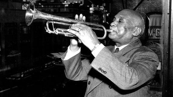 Der Vater des "St. Louis Blues", Trompeter W.C. Handy, sitzt vor einem offenen Fenster und spielt Trompete © picture alliance / ASSOCIATED PRESS 