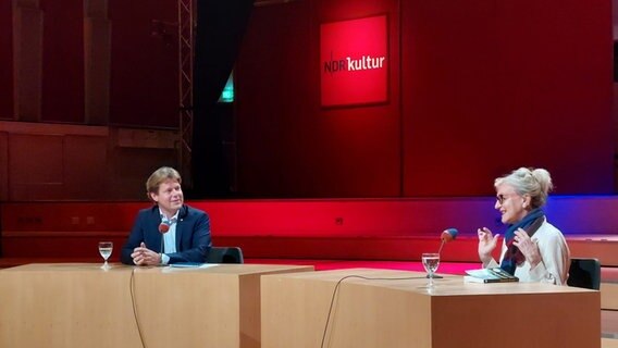 Jan Ehlert und Elizabeth Strout sitzen an Tischen auf einer Bühne. © NDR Foto: Alexander Solloch