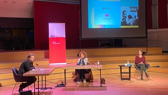 Alexander Solloch, Leïla Slimani und Franziska Hartmann sitzen an Tischen auf einer Bühne. © Literaturhaus Hamburg 