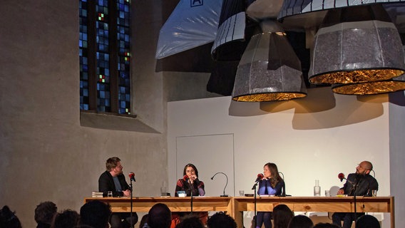 Alexander Solloch, Karosh Taha, Heike Geißler und Behzad Karim Khani sitzen auf einer Bühne vor Publikum. © Literaturhaus St. Jakobi Hildesheim 