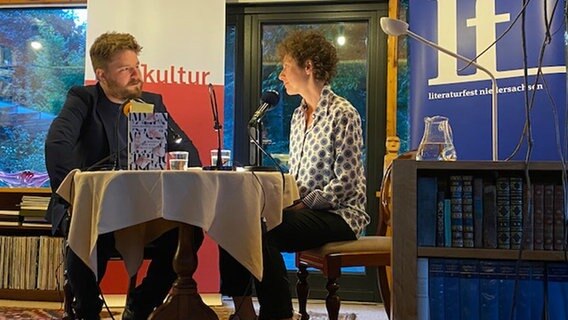Alexander Solloch und Sasha Marianna Salzmann im Gespräch sitzend an einem Tisch. © VGH-Stiftung Foto: Susanne Mamzed