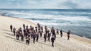 Musiker laufen zusammen am Strand an der Ostsee entlang. © Bernd Possardt 