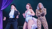Drei Darstellerinnen in unterschiedlichen Showbiz-Kostümen stehen auf der Bühne. © Kerstin Schomburg 