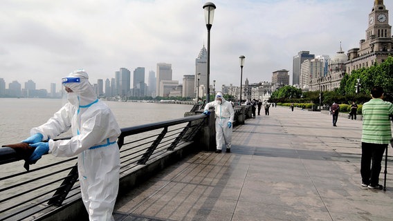 Menschen in weißen Anzügen desinfizieren öffentliche Plätze in Shanghai © picture alliance / ASSOCIATED PRESS Foto: Daisuek Kawase