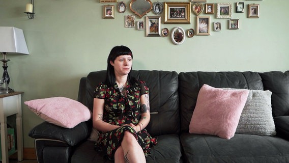 Shelby Lynn sitzt auf einem Sofa, hinter ihr an der Wand hängen gerahmte Fotos. © NDR 