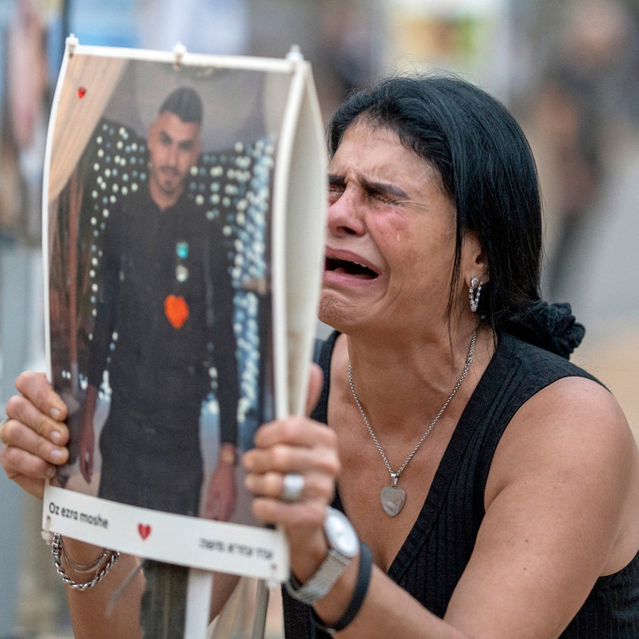 Eine weinende Frau hält ein Plakat hoch, auf dem ein junger Mann abgedruckt ist. © dpa Foto: Ilia yefimovich