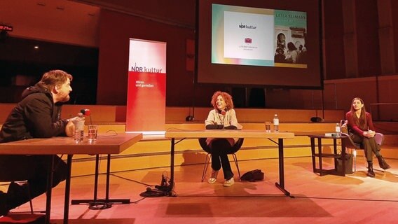 Franziska Schreiber liest vorne an einem Pult - im Hintergrund hört Leila Slimani gespannt zu. © NDR 
