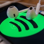 Auf einer Tastatur liegen ein Smartphone, auf dem das Spotify-Logo angezeigt wird, und ein Kopfhörer. © picture alliance / NurPhoto Foto: Jaap Arriens