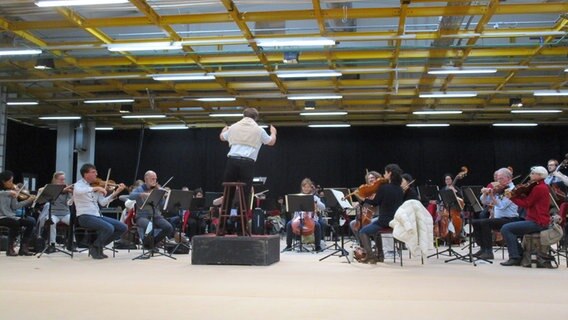 Ein Dirigent steht vor einem großen Orchester. © NDR Foto: Axel Seitz