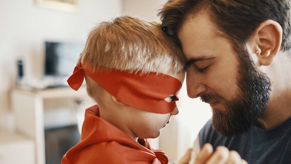 Kind mit rotem Umhang und Mann mit Bart © imago images/Westend61 