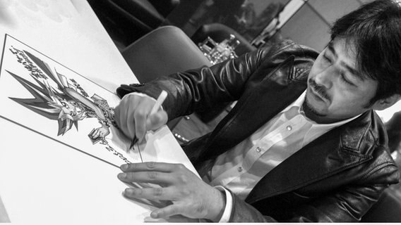 Ein Mann unterschreibt auf einem Bild © picture-alliance/ dpa/dpaweb | Peter Endig 