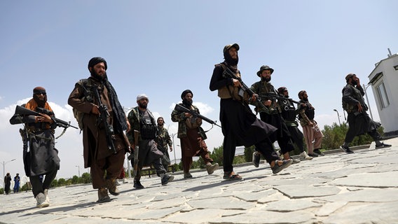 Schwer bewaffnete Taliban-Kämpfer patrouillieren nach ihrer Machtübernahme durch Kabul © picture alliance/dpa/AP Foto: Rahmat Gul