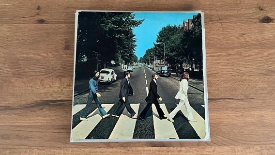 Das Cover der Platte "Abbey Road" von The Beatles liegt auf einem Tisch. © Apple 
