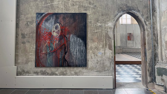 In der Kirche St. Jakobi hängt ein Gemälde an einer kahlen, grauen Wand. © NDR Foto: Janet Lindemann